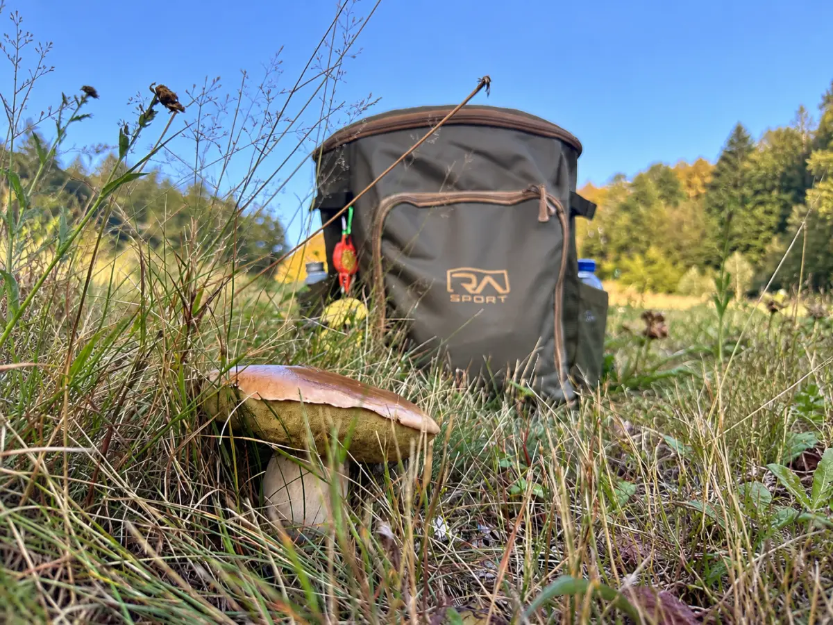 Zaino da funghi RA Sport RNG-9 da 30 litri in un prato di montagna, con un fungo porcino in primo piano.